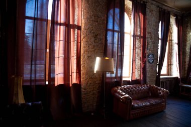 Boş bir kütüphane odasının camları ve tuğla bir duvar. Eski usul deri kanepe. Odadaki mobilyalar. İçi koyu kahverengi..