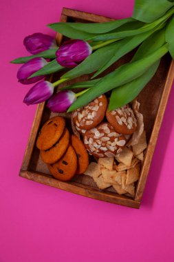 Farklı kurabiyeler. Yemek arkaplanı. Ev yapımı kahvaltı kurabiyesi manzarası. Tatlı badem cipsi. Fırın aşçısı. Pembe lale çiçekleri. Hindistan cevizi, hecelenen kuru üzüm.