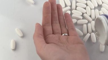 Eline bir doz tablet dök. Tablet tedavisi. Vitaminler, beslenme takviyesi, ağrı kesiciler ve antipiretikler. Eczacılık. Eczane. Beyaz haplar. Sağlık tedavisi