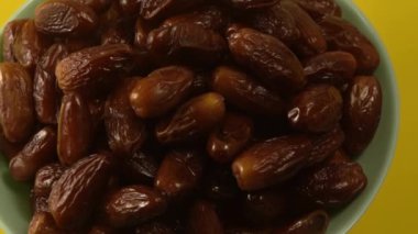 Tarihler. Hurmalıkların meyveleri. Sağlıklı bir atıştırmalık kasesi. Lezzetli kuru tarihler tabakta. Tarih hasadı Ramazan 'ı simgeliyor.