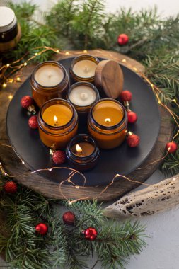 Soya mumları cam kavanozlarda yanar. Evdeki rahatlık. Kahverengi kavanozdaki mum. Koku ve ışık. Kokulu el yapımı mum. Aroma terapisi. Noel ağacı ve kış havası. Hoş bir dekor. Şenlikli çelenk dekorasyonu