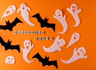 White ghosts and bat craft for Halloween party. Wrapping paper ghost on orange background top view. Cartoon creepy Whisper. DIY hand made. Set boo characters. Word wooden letter phrase.