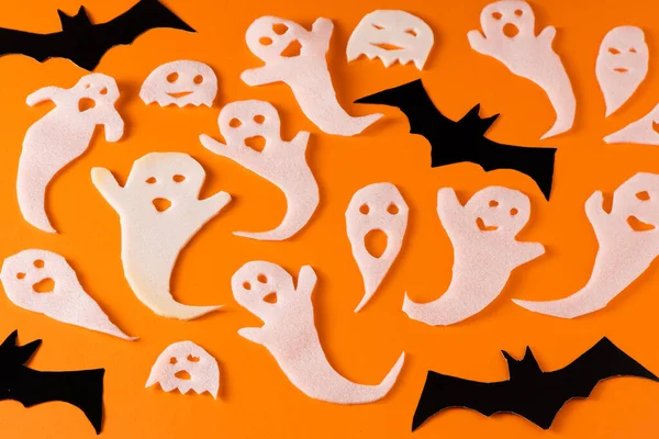 stock image White ghosts and bat craft for Halloween party. Wrapping paper ghost on orange background top view. Cartoon creepy Whisper. DIY hand made. Set boo characters.