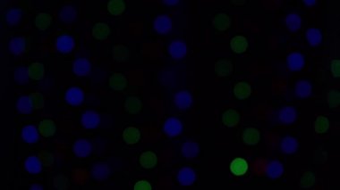 Bokeh çelenkleri yakıyor. Bulanık yumuşak odak. Çelenk yanıp sönüyor. Gece şehir ışıkları. Aralık 'ta Noel havası. Kışın ev penceresi. Siyah arkaplanda çok renkli ışık 4K görüntüsü.