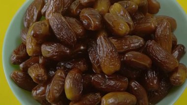 Tarihler. Hurmalıkların meyveleri. Sağlıklı bir atıştırmalık kasesi. Lezzetli kuru tarihler tabakta. Tarih hasadı Ramazan 'ı simgeliyor.