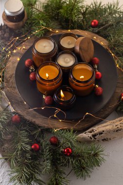 Soya mumları cam kavanozlarda yanar. Evdeki rahatlık. Kahverengi kavanozdaki mum. Koku ve ışık. Kokulu el yapımı mum. Aroma terapisi. Noel ağacı ve kış havası. Hoş bir dekor. Şenlikli çelenk dekorasyonu