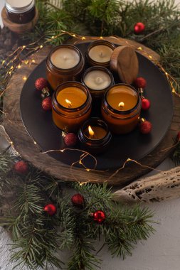 Soya mumları cam kavanozlarda yanar. Evdeki rahatlık. Kahverengi kavanozdaki mum. Koku ve ışık. Kokulu el yapımı mum. Aroma terapisi. Noel ağacı ve kış havası. Hoş bir dekor. Şenlikli çelenk dekorasyonu