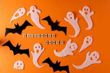 White ghosts and bat craft for Halloween party. Wrapping paper ghost on orange background top view. Cartoon creepy Whisper. DIY hand made. Set boo characters. Word wooden letter phrase.