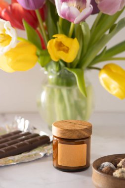 Cam bir kavanozda ahşap kapaklı soya aromalı mum. Uzay etiketini kopyala. Güzellik ve güzellik merkezi. Evde Aromaterapi. Kokulu mumlar hazır. Minimalizm estetik arka planı. Romantik bir ortam. Bahar laleleri.