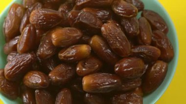 Tarihler. Hurmalıkların meyveleri. Sağlıklı bir atıştırmalık kasesi. Lezzetli kuru tarihler tabakta. Tarih hasadı Ramazan 'ı simgeliyor.