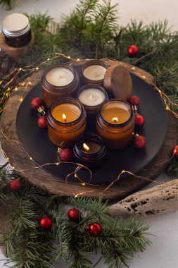 Soya mumları cam kavanozlarda yanar. Evdeki rahatlık. Kahverengi kavanozdaki mum. Koku ve ışık. Kokulu el yapımı mum. Aroma terapisi. Noel ağacı ve kış havası. Hoş bir dekor. Şenlikli çelenk dekorasyonu