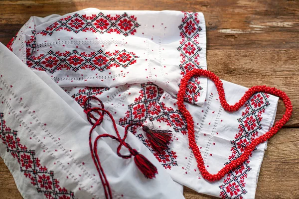 Ukrainian clothes embroidered white shirt. Red and black threads on a wooden background. Vyshyvanka is a symbol of Ukraine. Embroidery. Cross stitching.