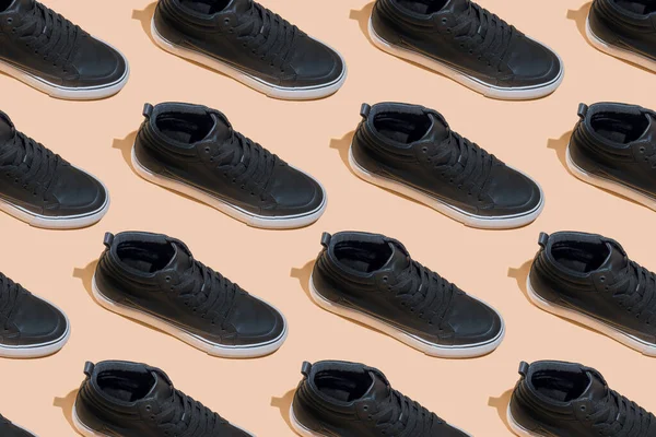 靴のパターン ベージュのパステルカラーの背景に影のある黒い靴 アクセサリーコンセプト 新しい革の靴 古典的なスポーツスタイル ファッションシューズ フラットミニマリズムストア広告 — ストック写真
