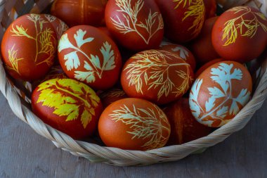 Paskalya yumurtaları soğan kabuğu, dereotu ve maydanozla boyanmış. Doğal ekolojik boyalar. Masanın üstünde yumurta sepeti var. Yemek arka planında. Bahar Ev Yapımı Paskalya Bayramı Zanaat Konsepti.