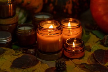 Soya mumları cam kavanozlarda yanar. Ağaç yaprakları. Evdeki rahatlık. Kahverengi kavanozdaki mum. Koku ve ışık. Kokulu el yapımı mum. Aroma terapisi. Sonbahar havası. Sonbaharda ev dekorasyonu. Şenlikli dekorasyon.