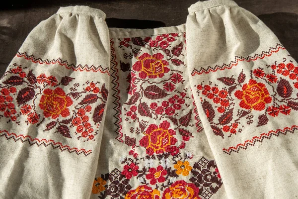 Ukrainian clothes embroidered shirt. Red orange and black threads background. Vyshyvanka is a symbol of Ukraine. Embroidery cross stitching. National Ukrainian stitch. Traditional clothing symbol.