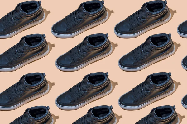 靴のパターン ベージュのパステルカラーの背景に影のある黒い靴 アクセサリーコンセプト 新しい革の靴 古典的なスポーツスタイル ファッションシューズ フラットミニマリズムストア広告 — ストック写真