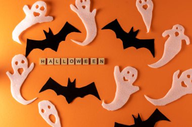 White ghosts and bat craft for Halloween party. Wrapping paper ghost on orange background top view. Cartoon creepy Whisper. DIY hand made. Set boo characters. Word wooden letter phrase.