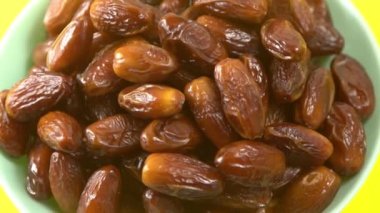 Tarihler. Hurmalıkların meyveleri. Sağlıklı bir atıştırmalık kasesi. Lezzetli kuru tarihler tabakta. Tarih hasadı Ramazan 'ı simgeliyor.