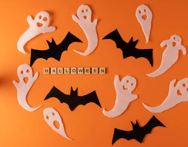 stock image White ghosts and bat craft for Halloween party. Wrapping paper ghost on orange background top view. Cartoon creepy Whisper. DIY hand made. Set boo characters. Word wooden letter phrase.