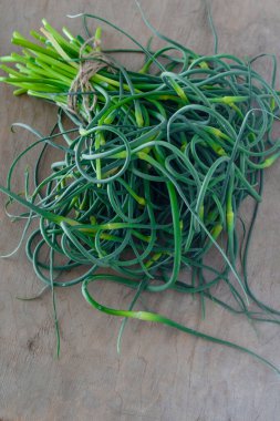 Sarımsaklı oklar. Masada bir sürü yeşillik var. Sebze, sağlıklı vitamin yiyeceği. Salata ve güveç için yeşil saplı fidanlar. Vejetaryen taze otlar, Çin mutfağı..