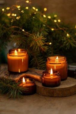 Soya mumları cam kavanozlarda yanar. Evdeki rahatlık. Kahverengi kavanozdaki mum. Koku ve ışık. Kokulu el yapımı mum. Aroma terapisi. Noel ağacı ve kış havası. Sıcak ev dekorasyonu. Şenlikli dekorasyon.
