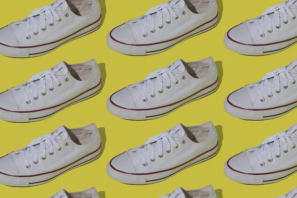 White sneakers pattern. Sports casual shoes on a yellow background. Top view.