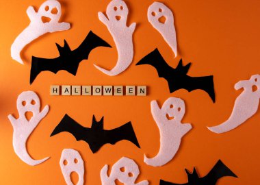 White ghosts and bat craft for Halloween party. Wrapping paper ghost on orange background top view. Cartoon creepy Whisper. DIY hand made. Set boo characters. Word wooden letter phrase.