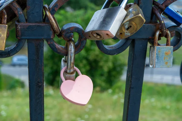 Pink lock in the shape of a heart. Locks for happiness, love and luck. Ritual and superstition. Tourist travel embankment. Heart lock copy space background.