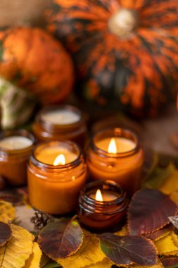 Soya mumları cam kavanozlarda yanar. Ağaç yaprakları, balkabağım. Evdeki rahatlık. Kahverengi kavanozdaki mum. Koku ve ışık. Kokulu el yapımı mum. Aroma terapisi. Sonbahar havası. Sonbaharda rahat ev dekorasyonu.