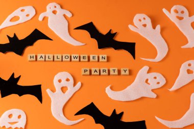 White ghosts and bat craft for Halloween party. Wrapping paper ghost on orange background top view. Cartoon creepy Whisper. DIY hand made. Set boo characters. Word wooden letter phrase.