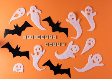 White ghosts and bat craft for Halloween party. Wrapping paper ghost on orange background top view. Cartoon creepy Whisper. DIY hand made. Set boo characters. Word wooden letter phrase.