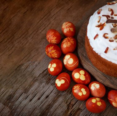 Paskalya yemeği geçmişi. Soğan kabuğu, yonca ve dereotu yapraklı kırmızı boyalı yumurtalar. Tahta bir masada paskalya pastası. Bahar ev yapımı DIY el işi. Renkli ev sade kahverengi yumurta üstü görünümü.