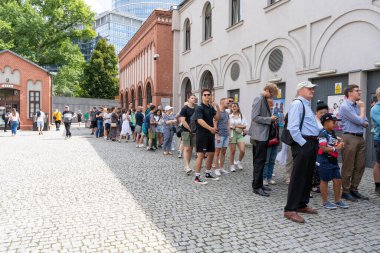 Varşova, Polonya - 1 Ağustos 2023. Bir sürü insan içeri girmek için dışarıda kuyrukta bekliyor. Varşova Ayaklanması Müzesi. Görüş. Tarihi Polonya anıtı. Açık hava Muzeum Powstania Warszawski egosu. Sıra sokağı