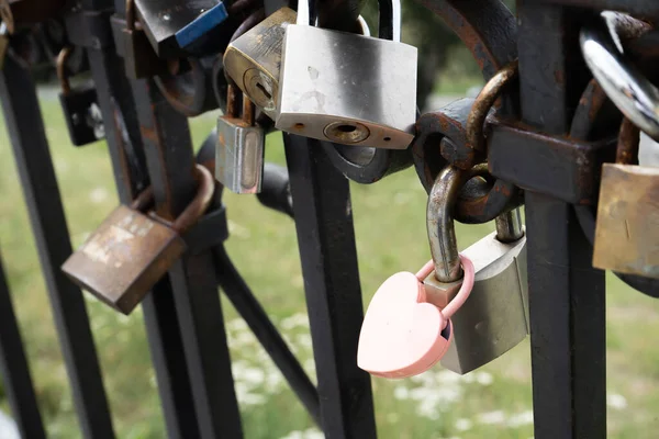 Pink lock in the shape of a heart. Locks for happiness, love and luck. Ritual and superstition. Tourist travel embankment. Heart lock copy space background.