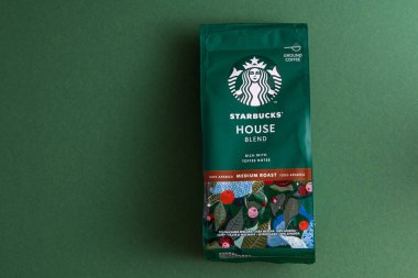 Starbucks kahve paketi. Yeşil desenli arka plan. Kahve çekirdeklerini şekerle karıştırın. Süpürge poşeti dolusu kahve. Marka logosu