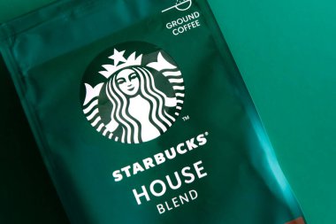 Starbucks kahve paketi. Yeşil desenli arka plan. Kahve çekirdeklerini şekerle karıştırın. Süpürge poşeti dolusu kahve. Marka logosu