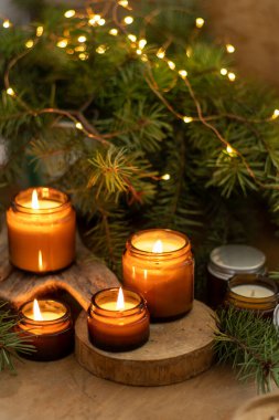 Soya mumları cam kavanozlarda yanar. Evdeki rahatlık. Kahverengi kavanozdaki mum. Koku ve ışık. Kokulu el yapımı mum. Aroma terapisi. Noel ağacı ve kış havası. Sıcak ev dekorasyonu. Şenlikli dekorasyon.