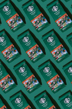 Starbucks kahve paketi. Yeşil desenli arka plan. Kahve çekirdeklerini şekerle karıştırın. Süpürge poşeti dolusu kahve. Marka logosu