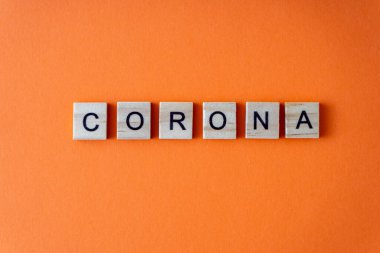 Corona kelimesi. Sözcük ahşap harflerle sıralanmış. Turuncu düz arkaplan