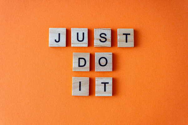 Просто скажи это слово. Фраза выложена деревянными буквами сверху. Мотивация. Оранжевый плоский фон