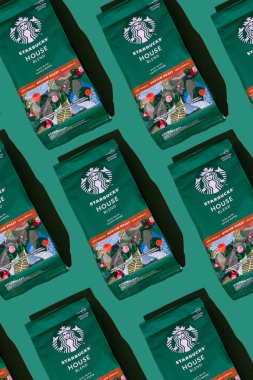Starbucks kahve paketi. Yeşil desenli arka plan. Kahve çekirdeklerini şekerle karıştırın. Süpürge poşeti dolusu kahve. Marka logosu