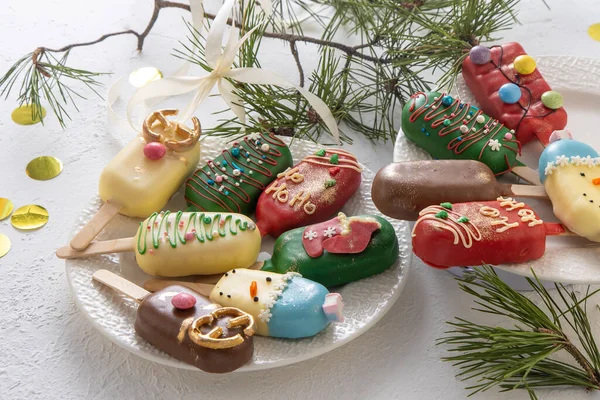 Christmas dessert. Sweet food. Cheesecake on a stick in the shape of ice cream. Childrens treat in winter. Candy Christmas tree, snowman, deer and Santa Claus. Gingerbread cookies.