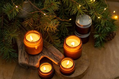 Soya mumları cam kavanozlarda yanar. Evdeki rahatlık. Kahverengi kavanozdaki mum. Koku ve ışık. Kokulu el yapımı mum. Aroma terapisi. Noel ağacı ve kış havası. Sıcak ev dekorasyonu. Şenlikli dekorasyon.