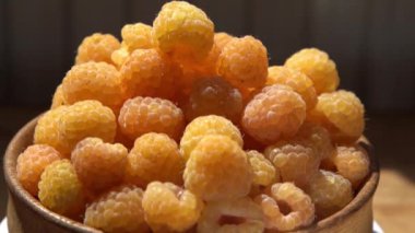 Masanın üzerindeki ahşap kasede sarı ahududular. Yaz meyveleri arka planı. Vitamin yiyecekleri, böğürtlen hasadı. Sağlıklı beslenme.