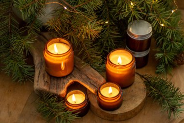 Soya mumları cam kavanozlarda yanar. Evdeki rahatlık. Kahverengi kavanozdaki mum. Koku ve ışık. Kokulu el yapımı mum. Aroma terapisi. Noel ağacı ve kış havası. Sıcak ev dekorasyonu. Şenlikli dekorasyon.