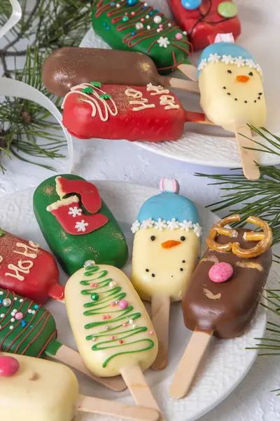 Christmas dessert. Sweet food. Cheesecake on a stick in the shape of ice cream. Childrens treat in winter. Candy Christmas tree, snowman, deer and Santa Claus. Gingerbread cookies.