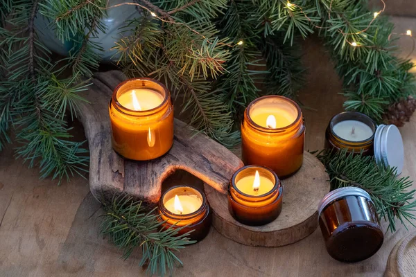 Soy candles burn in glass jars. Comfort at home. Candle in a brown jar. Scent and light. Scented handmade candle. Aroma therapy. Christmas tree and winter mood. Cozy home decor. Festive decoration.