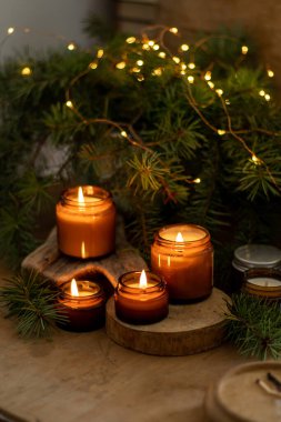 Soya mumları cam kavanozlarda yanar. Evdeki rahatlık. Kahverengi kavanozdaki mum. Koku ve ışık. Kokulu el yapımı mum. Aroma terapisi. Noel ağacı ve kış havası. Sıcak ev dekorasyonu. Şenlikli dekorasyon.