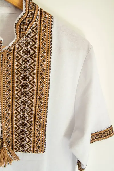 Ukrainian clothes embroidered shirt. Brown beige and white black threads background. Vyshyvanka symbol of Ukraine. Embroidery cross stitching. National Ukrainian stitch. Traditional clothing.